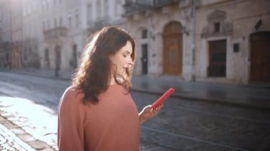 Beyaz bir kadının şehir caddesinde yürüdüğü yakın plan, cep telefonuyla konuştuğu, akıllı telefon kullanan esmer, telefonda arkadaşlarıyla konuşan gülen bir kadın.