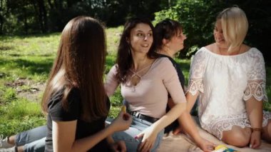 Güneşli bir yaz gününde, doğada sağlıklı beslenen bir grup arkadaş sepette jambonlu sandviç, doğada meyve, sandviç ve ikramla piknik.