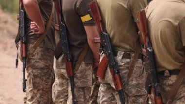Close-up of Ukrainian soldiers standing on the checkpoint with Kalashnikov assault rifles behind their backs, dressed in military uniforms.