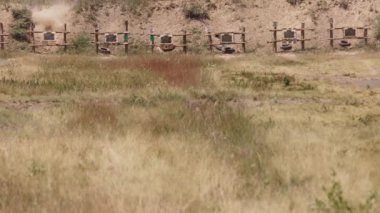 Bir askeri eğitim hedefine ateş edilir, tam hedefi vurur ve ordu eğitim görürken geçilir.