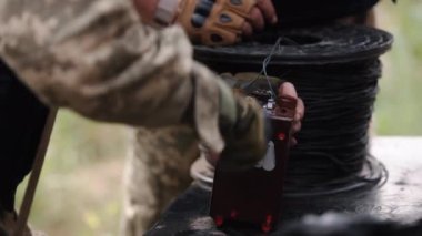 Soldier, anti-terrorist team combat engineer, ammunition technical officer, explosives military expert, saboteur in camouflage balaclava helmet and explosives in hand, miner preparing explosive device