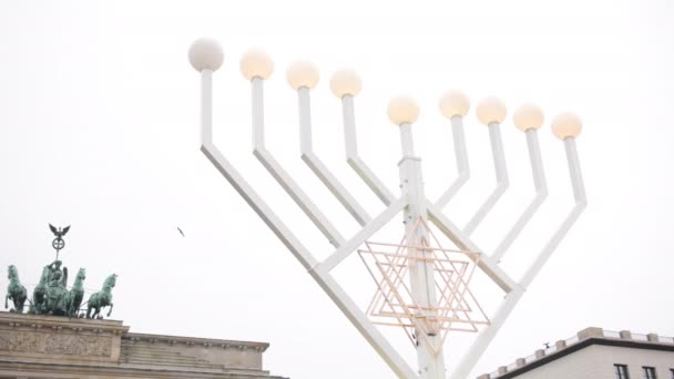 在德国柏林 犹太人在庆祝光明节时 用传统的烛台和蜡烛在外面点着闪闪发光的路灯 背景中的勃兰登堡门 — 图库视频影像