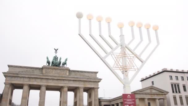 メノアの外の街灯の輝く光は 背景にあるユダヤ人のハヌカの祝日 ブランデンブルク門の伝統的なシンボルです — ストック動画