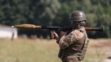 Üniformalı, miğferli ve çelik yelekli asker. Omzundan ateşlenen roket fırlatıcıları RPG-7 PSRL-1 düşmana ateş ediyor..
