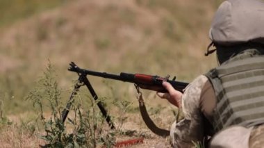 In green uniform vest, a military man unloads a machine gun, a soldier lies with a gun, Army war concept, military, army gunner attacking, Corps Machine Gun Crew shooting, Army Gunner attacking.