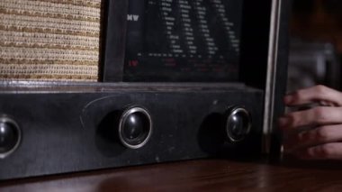 Müzik konseptini dinlerken, eski tarz, fm kanalı müzik çalıyor, stil sahibi retro radyo tribünleri, el kameraları yakın plan radyoyu açıyor, antika radyo alıcısı yaklaşık 1950 'lerde.