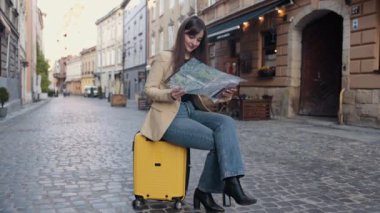 Yön, konum haritası, turist gezisi. Yazın yurtdışına seyahat eden mutlu bayan turist, haritada oteline giden yolu bulmak için bir atlas üzerinde yol tarifi arar.