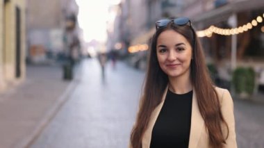 Esmer kadın, portre kadını, mutlu genç. Yakın plan portre, açık havada poz veren genç bir kadın, güzel bir beyaz kadın, gülümseyen mutlu bir kız ve anın tadını çıkarıyor..