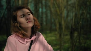 Yaz ormanında yalnız bir kız etrafına bakıyor ve hayal kuruyor.
