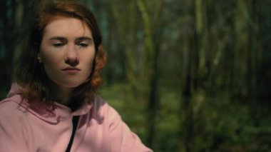 Yaz ormanında bir şeyler hatırlamaya çalışan yalnız bir kız. Yakın plan.