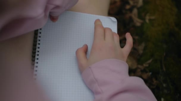 POV dívka-spisovatelka sedí v lese a přemýšlí nad prázdným papírem — Stock video