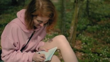 Ormandaki yazar kız bir deftere mesaj yazar, sevinç, yukarıdan bir kamera.