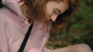 Yaz ormanında harika bir kız kağıda bir hikaye yazar ve gülümser, yakın plan.