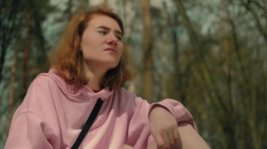 Orman kulelerindeki kızıl saçlı kız kameranın üstünde, iyice düşünüp bekliyor.