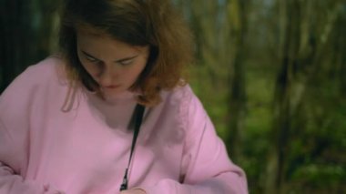 Ormandaki kız mükemmel kalemi arıyor. Kağıda yazar.