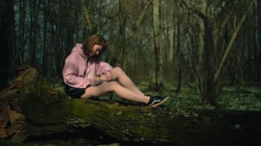 Ormandaki kız bir deftere yazar, sinirlenir, bir kalem ve çarşaf atar.