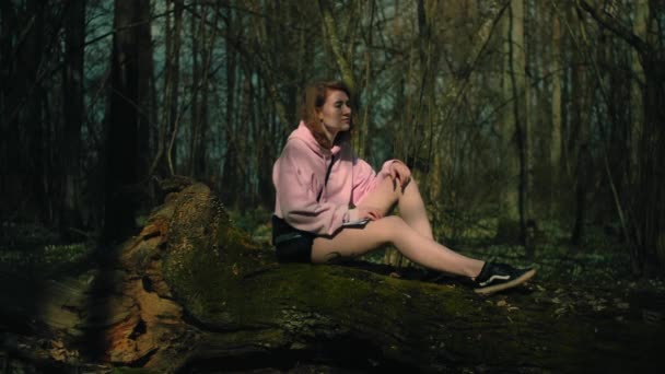 Eenzame vrouwen denkt hard na terwijl ze in een zomerbos aan een boom zitten, — Stockvideo