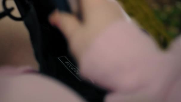 A nők rózsaszín kapucnis pulcsit adnak a táskájába tollat keresve. — Stock videók