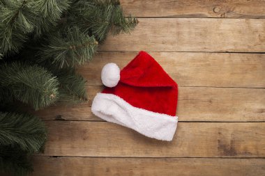 Noel arkaplanı. Noel Baba şapkası ve ağaç dalları ahşap arka planda. Üst manzara, düz uzanma.
