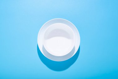 Temiz beyaz tabaklar, mavi arka planda tabaklar. Üst manzara, düz uzanma. 