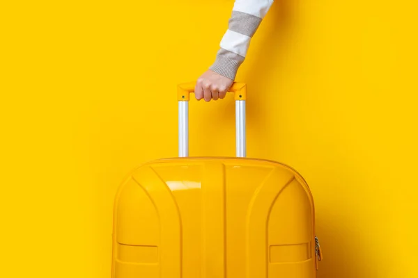 Weibliche Hand Hält Einen Gelben Koffer Auf Leuchtend Gelbem Hintergrund — Stockfoto