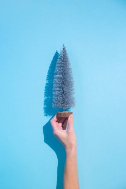 Mavi arka planda dekoratif bir Noel ağacı tutuyor. Pankart