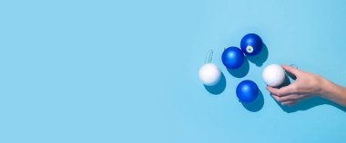 Soyut resim elinde mavi bir arkaplanda Noel ağacı süslemeleri var. Düz yatış, üst görünüm