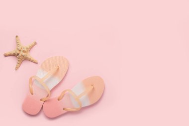 Plaj terlikleri, pembe arka planda deniz yıldızı. Üst manzara, düz uzanma 