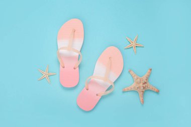 Plaj terlikleri, mavi arka planda deniz yıldızı. Üst manzara, düz uzanma