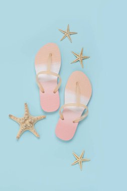 Plaj terlikleri, mavi arka planda deniz yıldızı. Üst manzara, düz uzanma
