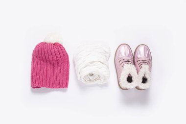 Pembe şapka, atkı, beyaz arka plandaki bir kız için çizmeler. Üst manzara, düz uzanma 