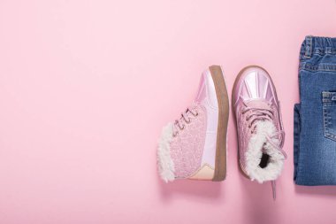 Pembe arka plandaki bir kız için bot ve kot pantolon. Üst manzara, düz uzanma 