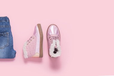 Pembe arka plandaki bir kız için bot ve kot pantolon. Üst manzara, düz uzanma 