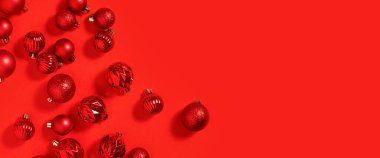 Güzel kırmızı küçük dekoratif toplar kırmızı bir arka fona saçılmıştır. Pankart 