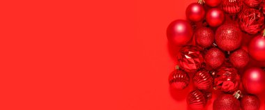 Güzel kırmızı küçük dekoratif toplar kırmızı bir arka fona saçılmıştır. Üst manzara, düz yatış. Pankart 