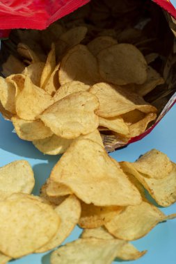 Mavi arka planda açık pakette taze patates cipsi.
