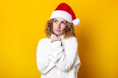 Sarı arka planda, Noel Baba şapkalı kıvırcık kadın.