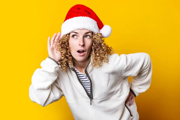 Lockige Junge Frau Mit Weihnachtsmann Hut Belauscht Auf Gelbem Hintergrund — Stockfoto