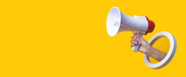 Female hand holds a megaphone in a round hole on a yellow background. Banner  clipart