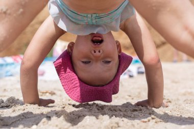 Sahilde mayo giymiş neşeli bir kız çocuğu oynanıyor.