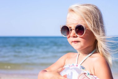 Güneşli bir günde plajda güneş gözlüklü güzel bir kız. 