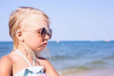 Güneşli bir günde plajda güneş gözlüklü güzel bir kız. 