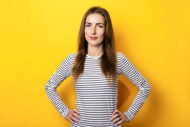 Sarı arka planda çizgili tişörtlü, güler yüzlü genç bayan..