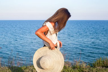 Uçurumun kenarında duran şapkalı genç bir kadın. 