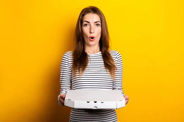 Surprised Shocked Young Woman Holding Packaged Pizza Yellow Background — стоковое фото
