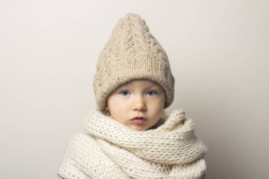 Hafif arka planda şapkalı güzel bir bebek. Çocuk duyguları kavramı, kış, alışveriş.