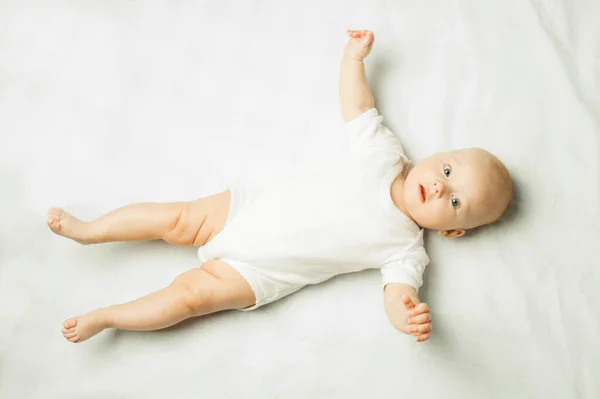 Bebé Con Vestido Blanco Acostado Boca Arriba Sobre Una Sábana — Foto de Stock