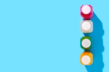 Mavi arka planda plastik şişelerde renkli detoks içeceği. Üst manzara, düz uzanma