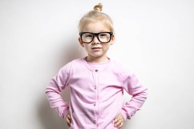 Gözlüklü, pembe süveterli, açık arkaplanda güzel bir kız çocuğu.