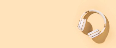 Bej arka planda kablosuz kulaklık. Düz yerde, üst tarafta. Pankart 